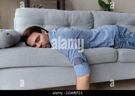 Erschöpfter Mann, der zu Hause auf einer bequemen Couch liegt und schläft Stockfoto