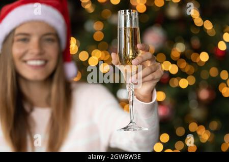 Glückliche junge Frau im Weihnachtshut, die Champagner trinkt Stockfoto