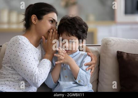 Junge asiatische Mutter erzählt Geheimnis zu kleinen Sohn. Stockfoto