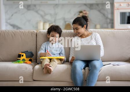 Lächelnde junge indische Frau, die während der Pause mit einem kleinen Kind spielt. Stockfoto