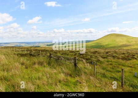 Blick über Moorland in Richtung Kirk Hill in den schottischen Grenzen mit Holzfarmtor und Drahtzaun im Vordergrund Stockfoto