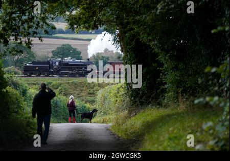 Die Leute sehen die BR Standard Class 4MT-Nr. an 76017 führt über die Mid Hants Railway, auch bekannt als Watercress Line, eine Dampfeisenbahn aus dem 3. Jahrhundert in Hampshire, am. Tag der Herbst-Dampfgala von Arlesford nach Ropley. Die diesjährige Herbst-Dampfgala, in Zusammenarbeit mit dem Somerset und Dorset Railway Trust, stellt die Somerset- und Dorset-Eisenbahn aus den 50er und 60er Jahren wieder her. Bilddatum: Sonntag, 3. Oktober 2021. Stockfoto