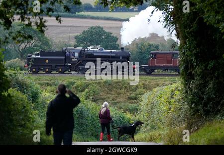 Die Leute sehen die BR Standard Class 4MT-Nr. an 76017 führt über die Mid Hants Railway, auch bekannt als Watercress Line, eine Dampfeisenbahn aus dem 3. Jahrhundert in Hampshire, am. Tag der Herbst-Dampfgala von Arlesford nach Ropley. Die diesjährige Herbst-Dampfgala, in Zusammenarbeit mit dem Somerset und Dorset Railway Trust, stellt die Somerset- und Dorset-Eisenbahn aus den 50er und 60er Jahren wieder her. Bilddatum: Sonntag, 3. Oktober 2021. Stockfoto