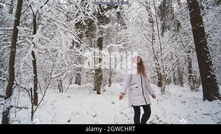 Ein Mädchen im Teenageralter geht durch den verschneiten Wald. Stockfoto