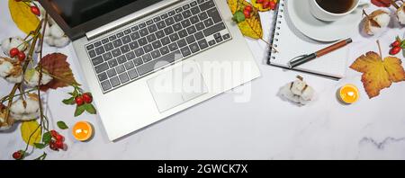 Herbst-Desktop mit Laptop-Computer-Tastatur, Notizblock, bunten Blättern und Kerzen, saisonales Home Office im Panorama-Format mit Kopierfläche, High-ang Stockfoto