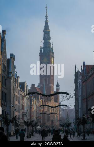 DANZIG, POLEN - 2020. JANUAR 17. Uhrenturm des Danziger Rathauses zu Weihnachten mit Menschen, die auf der Straße spazieren. Stockfoto