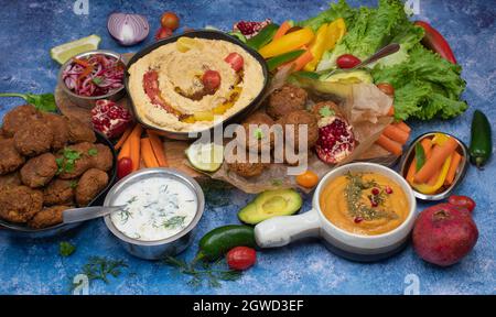 Mediterrane Speisen mit Hummus, Falafel, geröstetem Pfefferdip, Joghurtsauce, Kruditen Stockfoto