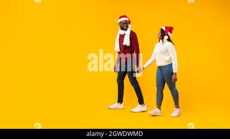 Weihnachtswerbung. Lächelndes Afroamerikanisches Paar Mit Weihnachtsmücken In Pose Hände Halten, Die Für Weihnachten Oder Neujahr In Der Nähe Des Freiraums Stehen Stockfoto