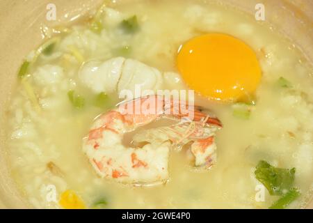 Reis Haferbrei Garnelen und Tintenfisch mit Ingwer Belag Eigelb auf Schüssel Stockfoto
