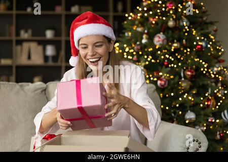 Glücklich aufgeregt Weihnachten Mädchen in Weihnachtsmann Hut Auspacken empfangen Box Stockfoto