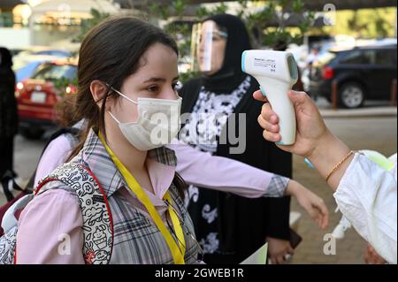 (211003) -- HAWALLI GOVERNORATE, 3. Oktober 2021 (Xinhua) -- Ein Schularbeiter überprüft die Körpertemperatur eines Studenten am Eingang einer Schule, die während der COVID-19-Pandemie im Hawalli Governorate, Kuwait, 3. Oktober 2021 wiedereröffnet wurde. Tausende von Studenten in ganz Kuwait kehrten am Sonntag in ihre Klassen zurück, als das Land beschloss, die Schulen nach 18 Monaten Schließung aufgrund der COVID-19-Pandemie wieder zu eröffnen. (Foto von Asad/Xinhua) Stockfoto