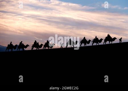 Dunhuang, Chinas Provinz Gansu. Oktober 2021. Touristen reiten auf Kamelen im malerischen Gebiet des Mingsha-Berges und der Halbmond-Quelle während des laufenden Nationalfeiertags in Dunhuang, nordwestlich der chinesischen Provinz Gansu, am 3. Oktober 2021. Quelle: Zhang Xiaoliang/Xinhua/Alamy Live News Stockfoto