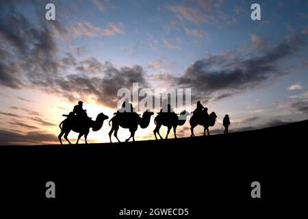 Dunhuang, Chinas Provinz Gansu. Oktober 2021. Touristen reiten auf Kamelen im malerischen Gebiet des Mingsha-Berges und der Halbmond-Quelle während des laufenden Nationalfeiertags in Dunhuang, nordwestlich der chinesischen Provinz Gansu, am 3. Oktober 2021. Quelle: Zhang Xiaoliang/Xinhua/Alamy Live News Stockfoto