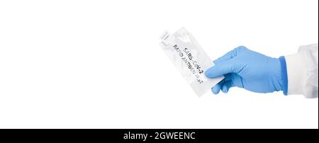 Hand des medizinischen Personals mit Umschlag des Covid-19-Antigen-Schnelltestkits auf weißem Hintergrund, Coronavirus-Infektionsschutzkonzept Stockfoto