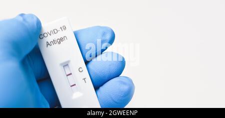 Medizinisches Personal zeigt Covid-19-positives Testergebnis des Antigen-Schnelltest-Kits auf weißem Hintergrund, Kopierraum, Coronavirus Infektiöse Protecept. Stockfoto