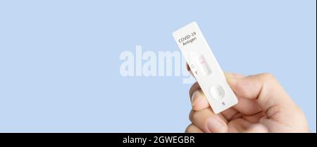 Eigene Hand mit negativem Covid-19-Testergebnis mit SARS CoV-2 Rapid Antigen Test Kit (ATK) und blauem Hintergrund mit Kopierraum, Coronavirus infektiös Stockfoto