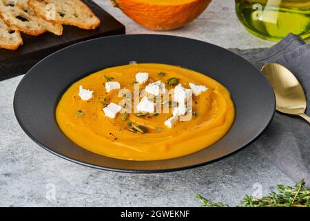 Saisonale Kürbiscremesuppe mit Feta-Käse, Samen, Thymian, Toast und Olivenöl Stockfoto