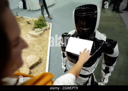 Frau, die einen Touchscreen eines Roboters an der Rezeption verwendet Stockfoto