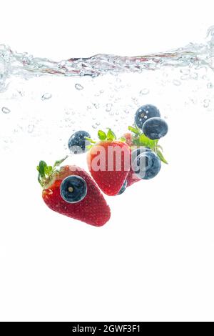 Erdbeere und Heidelbeere, die ins Wasser spritzt, Sommergetränk-Konzept Stockfoto