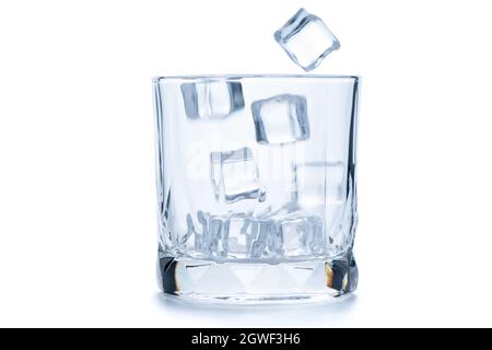 Lassen Sie Eiswürfel in ein leeres Steinglas oder altmodisches Glas fallen, das auf weißem Hintergrund isoliert ist, Glaswaren-Konzept Stockfoto