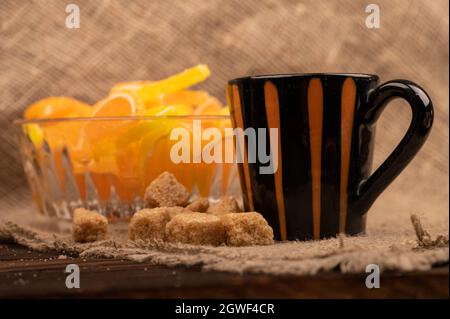 Bunte, geformte Marmeladenscheiben in einer Glasvase, Stücke braunen Rohrzuckers und eine Tasse Kaffee, Nahaufnahme, selektiver Fokus Stockfoto