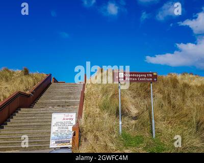 Petten aan Zee, Noord-Holland, Niederlande. 17. April 2021. Treppe über dem Deich am Eingang zum Strand an der niederländischen Küste, eine Informationspost Stockfoto