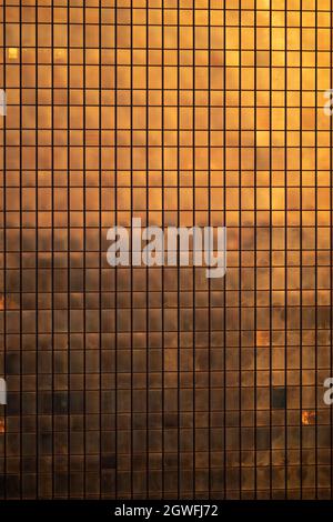 Wolkenkratzer-Gebäudefenster bei Sonnenuntergang, moderne Gebäudeglasfassade, die von der goldenen Farbe der untergehenden Sonne beleuchtet wird, Marriott Hotel, Polen. Stockfoto