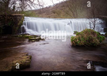 Langzeitbelichtung des Monsal Dale Weir Wasserfalls und des Flusses Wye auf dem Monsal Trail im Peak District Stockfoto
