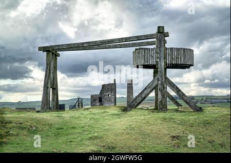 Der nachgebaute hölzerne Pferdegin mit entferntem Maschinenhaus und Kamin in der Magpie Mine, Sheldon, einer erhaltenen Bleimine im Peak District National Park Stockfoto