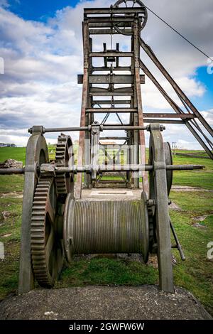 Das metallene Grubenkopf-Wickelrad, der Käfig und die Kopfbedeckung über dem Hauptgang der Magpie Mine, Sheldon, einer erhaltenen Bleimine im Peak District National Pa Stockfoto