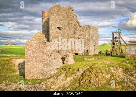 Das kornische Maschinenhaus, ein kreisförmiger Kamin und ein Drehgetriebe mit Grubenkopf bei der Magpie Mine, Sheldon, einer erhaltenen Bleimine im Peak District National Park Stockfoto