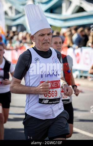 London, Großbritannien. Oktober 2021. Ein Mann in einem Köchhut beim London Marathon 2021 in der Tower Bridge in London, Großbritannien, gelaufen. Kredit: SMPNEWS / Alamy Live Nachrichten Stockfoto