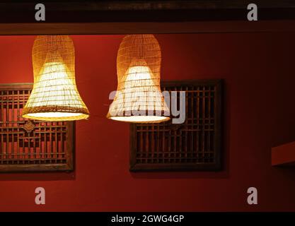 Lampenschirm aus Bambus und rote Wand mit Holzfensterrahmen Dekoration Stockfoto