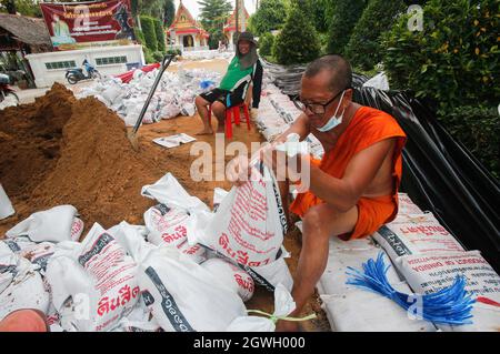 Ein buddhistischer Mönch sah, wie er eine Sandsackwand baute, um einen Damm zu schaffen, als Wasser vom Chao Phraya Fluss zu einem Tempel in der Provinz Pathum Thani überfließt. Der Einfluss des Sturms von Dianmu, der das Land trifft, hat die Befürchtungen verstärkt, dass sich die Mega-Überschwemmungen, die das Flussbecken des Chao Phraya vor 10 Jahren heimgesucht haben, wiederholen werden. Diese Katastrophe verursachte Schäden von über 100 Milliarden Baht. Obwohl viele Wasserexperten die Befürchtungen zerstreuen und sagen, dass die Wassermenge im Flussbecken in diesem Jahr im Vergleich zur großen Überschwemmung im Jahr 2011 deutlich geringer ist, gibt es dennoch viele Ähnlichkeiten. (Foto von Chaiwat Stockfoto