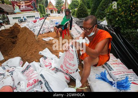 Ein buddhistischer Mönch sah, wie er eine Sandsackwand baute, um einen Damm zu schaffen, als Wasser vom Chao Phraya Fluss zu einem Tempel in der Provinz Pathum Thani überfließt. Der Einfluss des Sturms von Dianmu, der das Land trifft, hat die Befürchtungen verstärkt, dass sich die Mega-Überschwemmungen, die das Flussbecken des Chao Phraya vor 10 Jahren heimgesucht haben, wiederholen werden. Diese Katastrophe verursachte Schäden von über 100 Milliarden Baht. Obwohl viele Wasserexperten die Befürchtungen zerstreuen und sagen, dass die Wassermenge im Flussbecken in diesem Jahr im Vergleich zur großen Überschwemmung im Jahr 2011 deutlich geringer ist, gibt es dennoch viele Ähnlichkeiten. Stockfoto