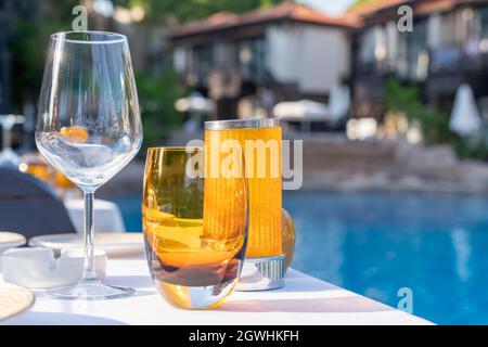 Tischeinstellung. Leere Gläser auf dem Hintergrund des Pools. Service der Gäste im Hotel im Sommer im Urlaub, Hintergrund. Stockfoto