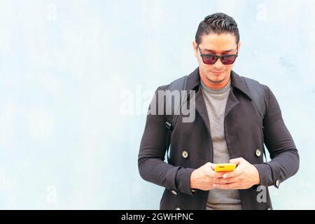 Junger Mann, der mit dem Handy die Straße entlang läuft Stockfoto