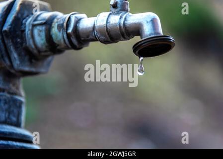 Tropfen Wasser, der aus einem schlecht geschlossenen Wasserhahn fällt. Stockfoto