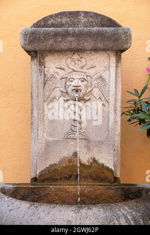 Nahaufnahme eines antiken Brunnens mit einer Caduceus-Skulptur Stockfoto