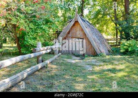 Ein alter, mit Schilf bedeckter Keller und ein Strohdach im Sommergarten eines Landguts. Stockfoto