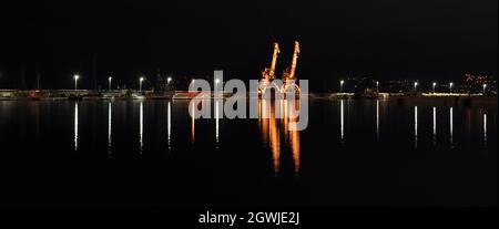 Rijeka Cargo Port bei Nacht. Abendansicht des Hafens von Rijeka in Kroatien. EIN LIEBESPAAR VON HAFENKRANEN AN DER HAUPTPEITSCHE. Stockfoto