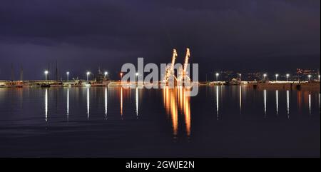 Rijeka Cargo Port bei Nacht. Abendansicht des Hafens von Rijeka in Kroatien. EIN LIEBESPAAR VON HAFENKRANEN AN DER HAUPTPEITSCHE. Stockfoto