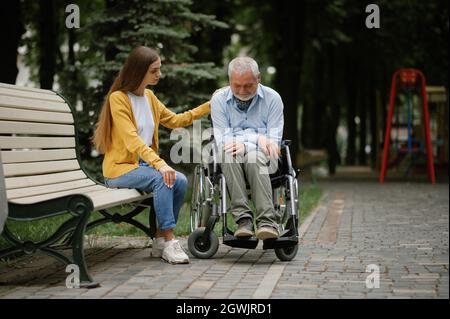 Frau kümmert sich um behinderte Vater im Rollstuhl Stockfoto
