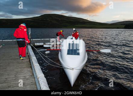 Männer starten ein Ruderboot auf dem Whitesadder Reservoir für ein Training für Atlantic Challenge, East Lothian, Schottland, Großbritannien Stockfoto