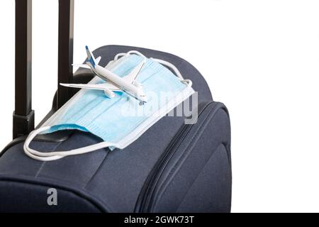 Reisevorbereitungen nach dem Ende der Quarantäne. Neues Leben nach Pandemie und Prävention von Coronavirus (COVID-19) Konzept. Gepäck mit Gesichtsmaske und Modell Stockfoto