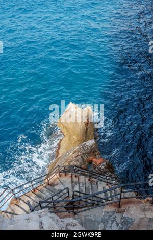 Eine Nahaufnahme von oben auf ein wunderschönes Steingebäude mit Treppen und Metallzaun im Ozean Stockfoto