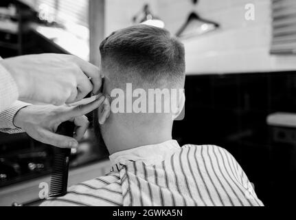 Barbier macht moderne Frisur von brutalen bärtigen Kerl im Salon. Mann im Friseurladen Stockfoto