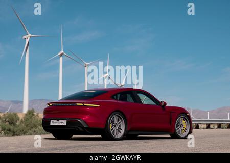 Antalya, Türkei 1. Oktober 2021: Ein kirschmetallisches, elektrisches Modell, Porsche Taycan Turbo S vor Windkraftanlagen. Stockfoto