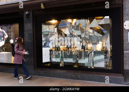 London, Großbritannien. September 2021. Die junge Frau packte ihr Mittagessen aus, während sie an einem Schaufenster des Ladens entlang geht, das mit Champagner gefüllt ist. Stockfoto