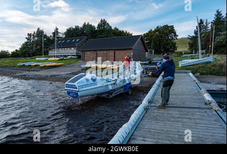 Männer starten ein Ruderboot auf dem Whitesadder Reservoir für ein Training für Atlantic Challenge, East Lothian, Schottland, Großbritannien Stockfoto